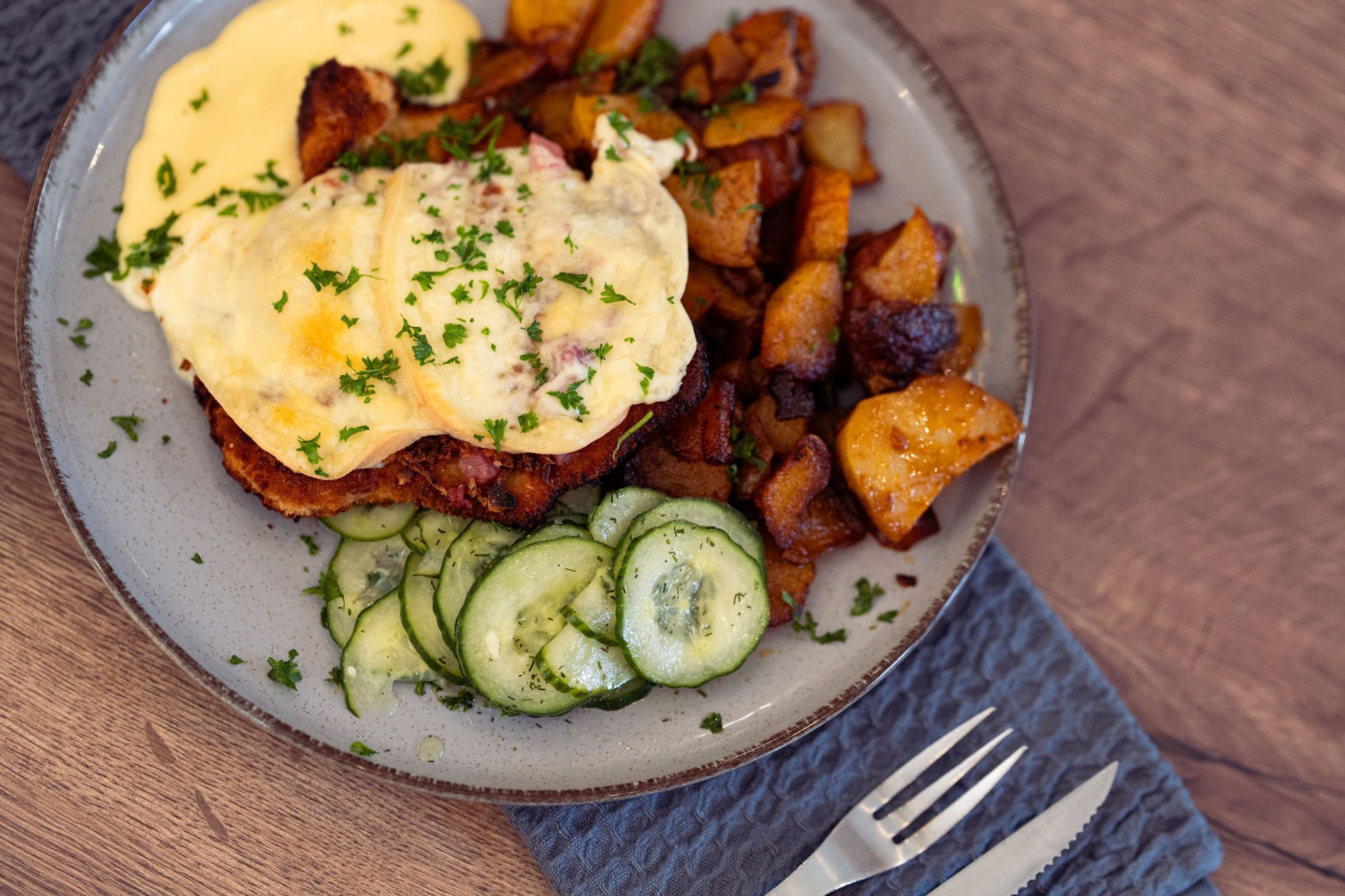 Une assiette avec un sandwich, des pommes de terre et des tranches de concombre.
