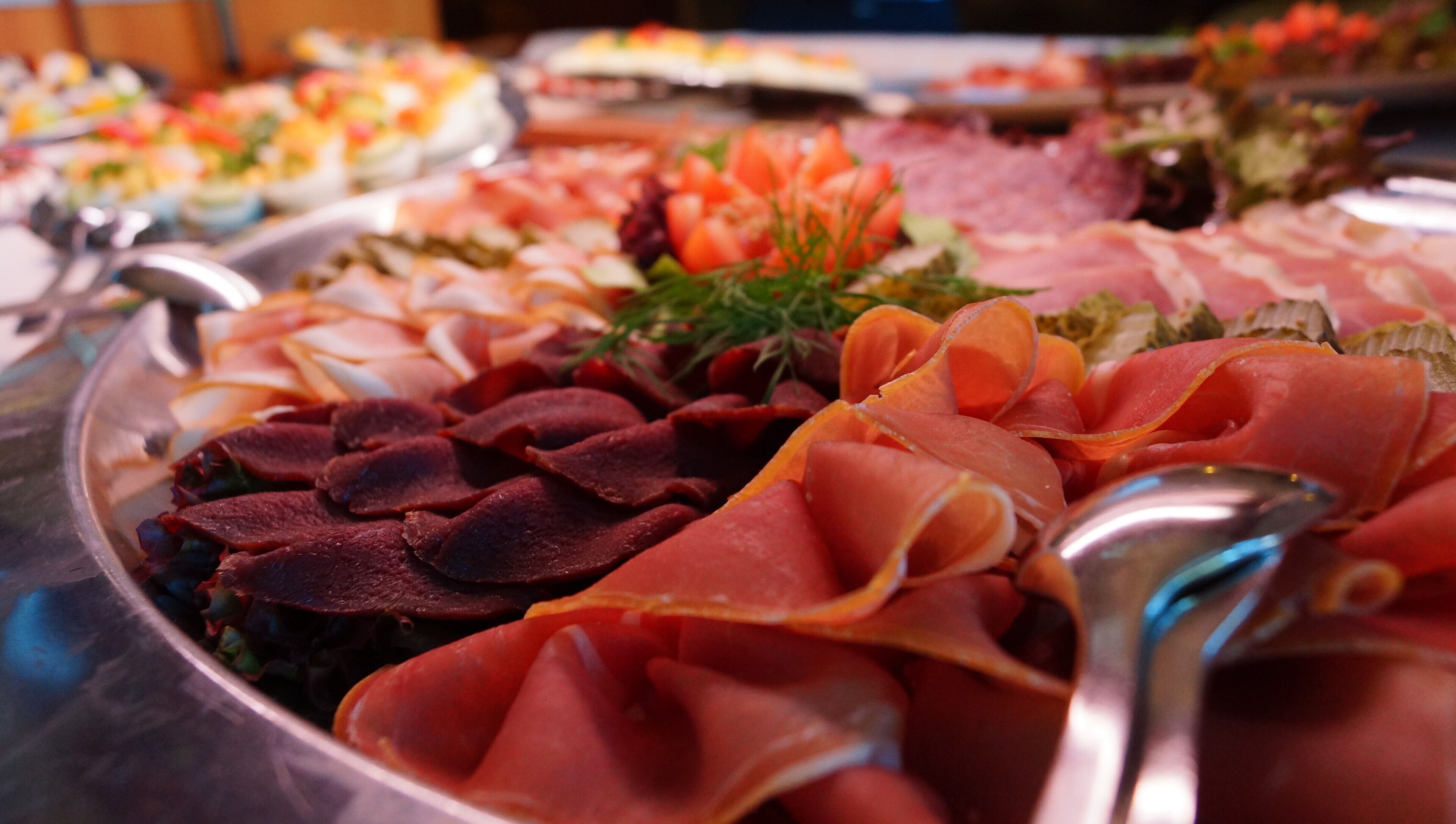 Een buffet met diverse gerechten, waaronder vlees en salades.