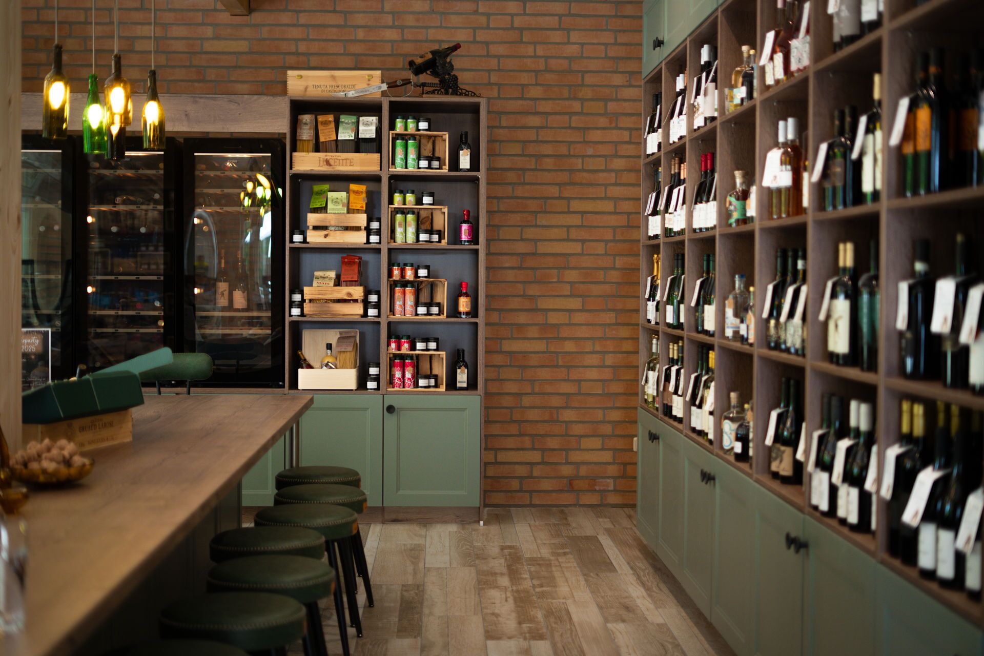 A bar area with stools, a wooden counter, and shelves stocked with bottles and jars.