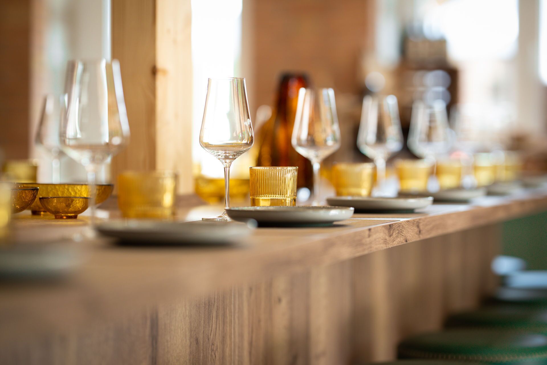 Una fila de copas y recipientes de vino vacíos sobre una barra de madera.