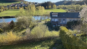 Een gebouw met twee verdiepingen en een plat dak, omgeven door weelderige begroeiing en een waterpartij.