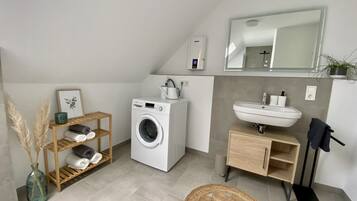Un baño moderno con lavadora, lavamanos y espejo.