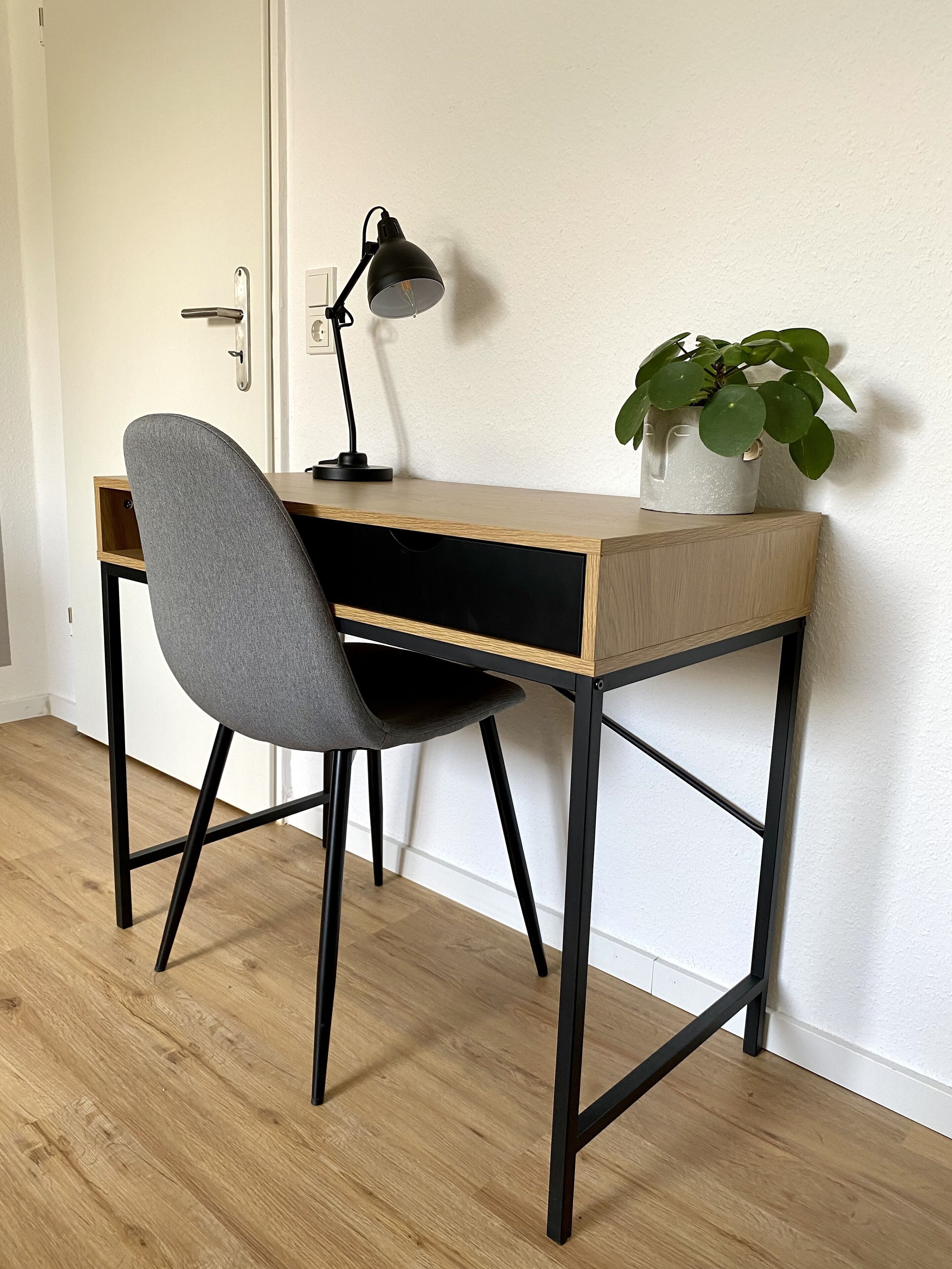 A desk with a chair, a lamp, and a potted plant.