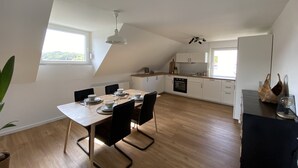Een moderne keuken met een eetgedeelte, met een houten tafel, stoelen en een inbouwoven.