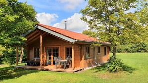 A wooden cabin with a red roof, large windows, and a patio with outdoor furniture. - Ecological new-build wooden block vacation home - free AlbCard from 2025  (Hayingen)