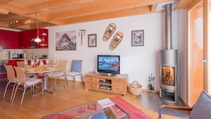 A modern living room with a fireplace, dining area, and kitchen.