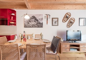 Ein Essbereich mit Holztisch, Korbstühlen und einem roten Schrank.