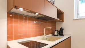 Una cucina compatta con piano cottura integrato, lavello e macchina da caffè.