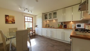 Una cucina moderna con mobili bianchi, piano cottura a gas, forno a microonde e macchina da caffè.