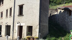 A building with multiple windows, a door, and a small garden with white flowers.