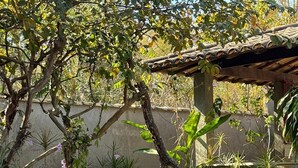Une cour avec des tables et des bancs en pierre, entourée de différentes plantes et d’arbres.