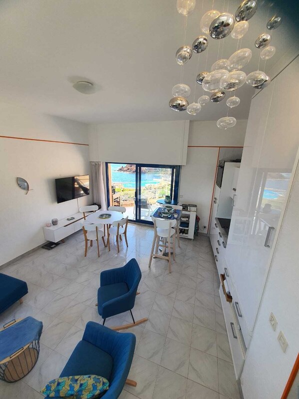 A modern living room with a dining area, a TV, and a view of the sea. - Waterfront apartment (Saint-Raphaël)