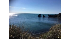 Un paysage côtier caractérisé par une eau d’un bleu limpide, des formations rocheuses et une végétation clairsemée.