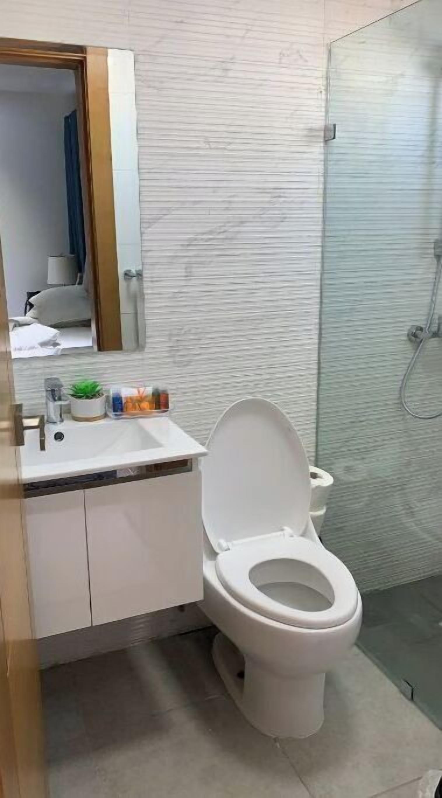A bathroom with a toilet, sink, and shower.
