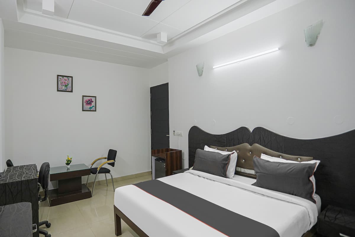 A bedroom with a bed, bedside tables, a desk, and chairs.