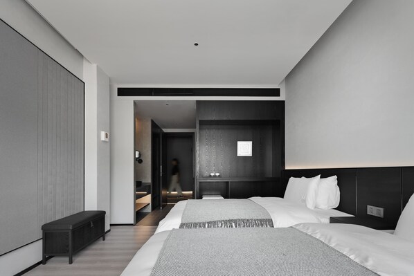 Una habitación de hotel moderna con dos camas, un banco y un vestidor.
