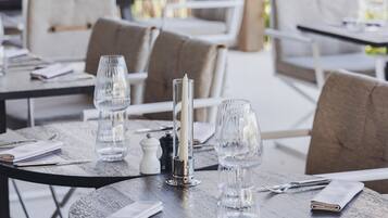 A restaurant setting with round tables, each set with a candle, glass, and cutlery.