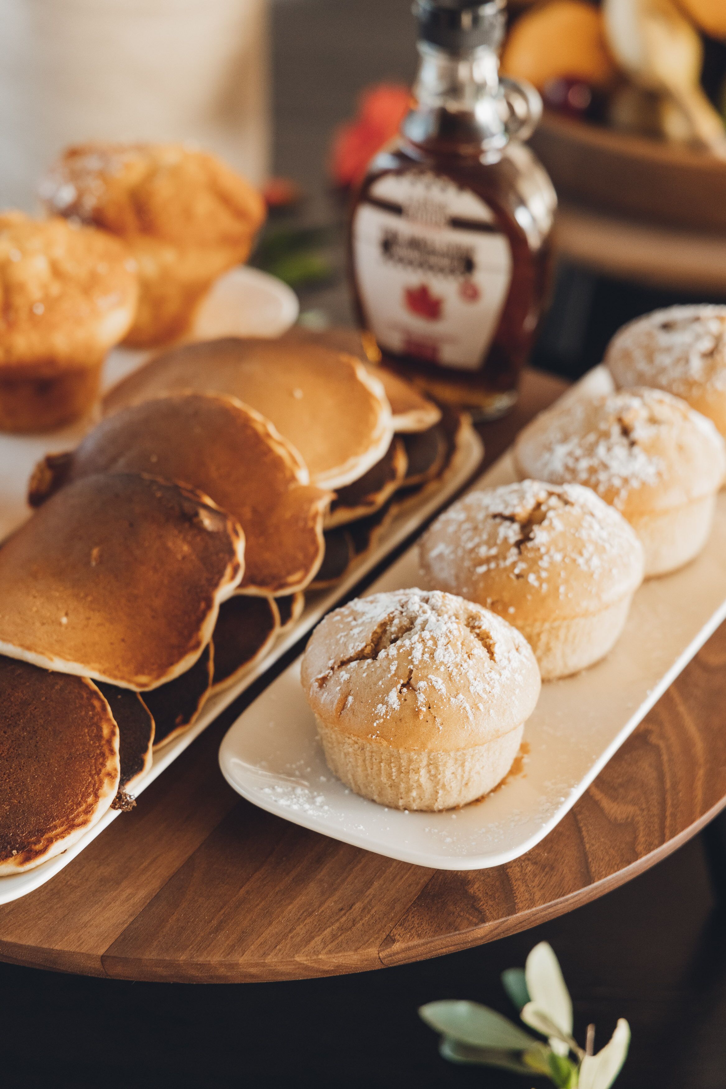 Uma mesa de madeira com panquecas e muffins.