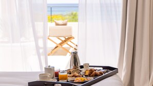 A breakfast tray on a bed with a view of the sea and a chair outside. - Casa Paradisu (Monticello)