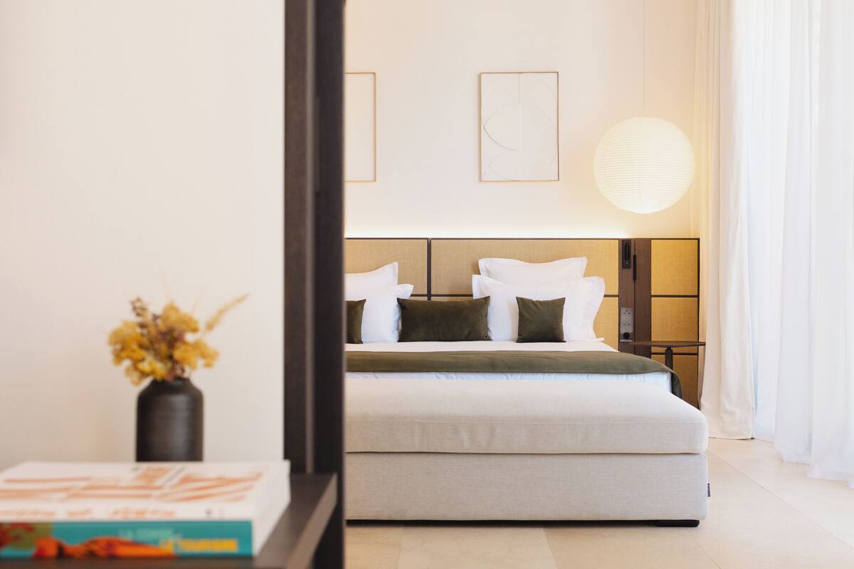A modern bedroom with a bed, bedside table, and a vase with flowers.