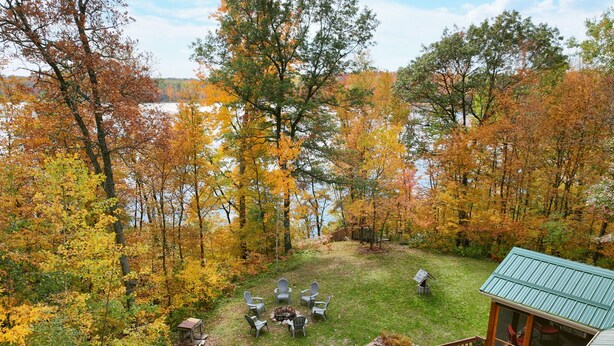 A deck with outdoor seating and a view of a lake surrounded by autumn trees.