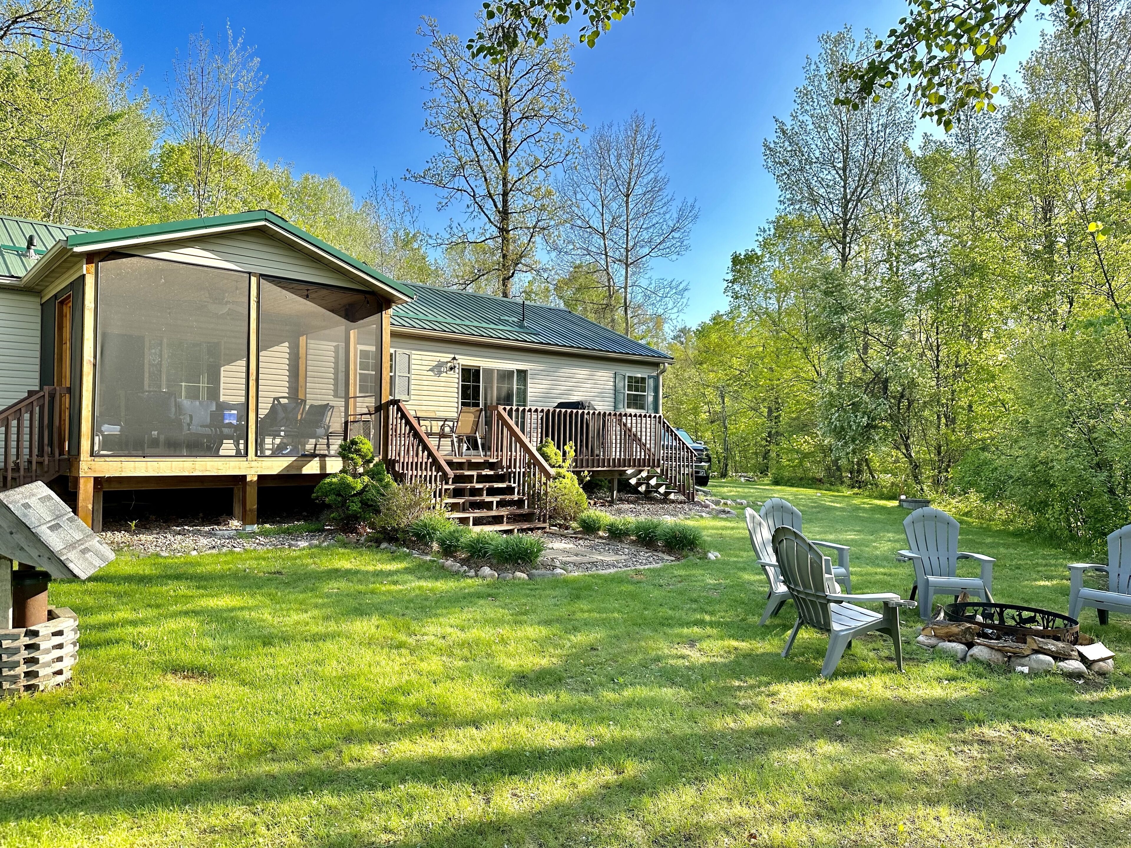 A cabin with a screened porch, a deck, and a fire pit area.