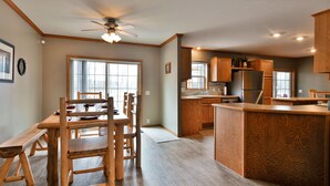 A spacious kitchen with wooden cabinetry, a central island, and a dining area with a bench and chairs.