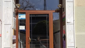 A wooden door with glass panels, a bell, and a small step leading up to the entrance. - On the Metro Station of Korydallos, Near Peiraeus (Korydallos)
