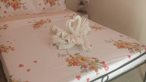 A neatly made bed with floral bedding and a decorative towel. - On the Metro Station of Korydallos, Near Peiraeus (Korydallos)