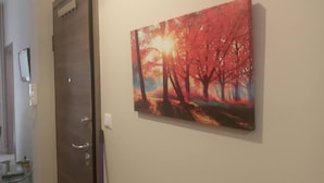 A hallway with a door and a painting of a sunset over trees. - On the Metro Station of Korydallos, Near Peiraeus (Korydallos)
