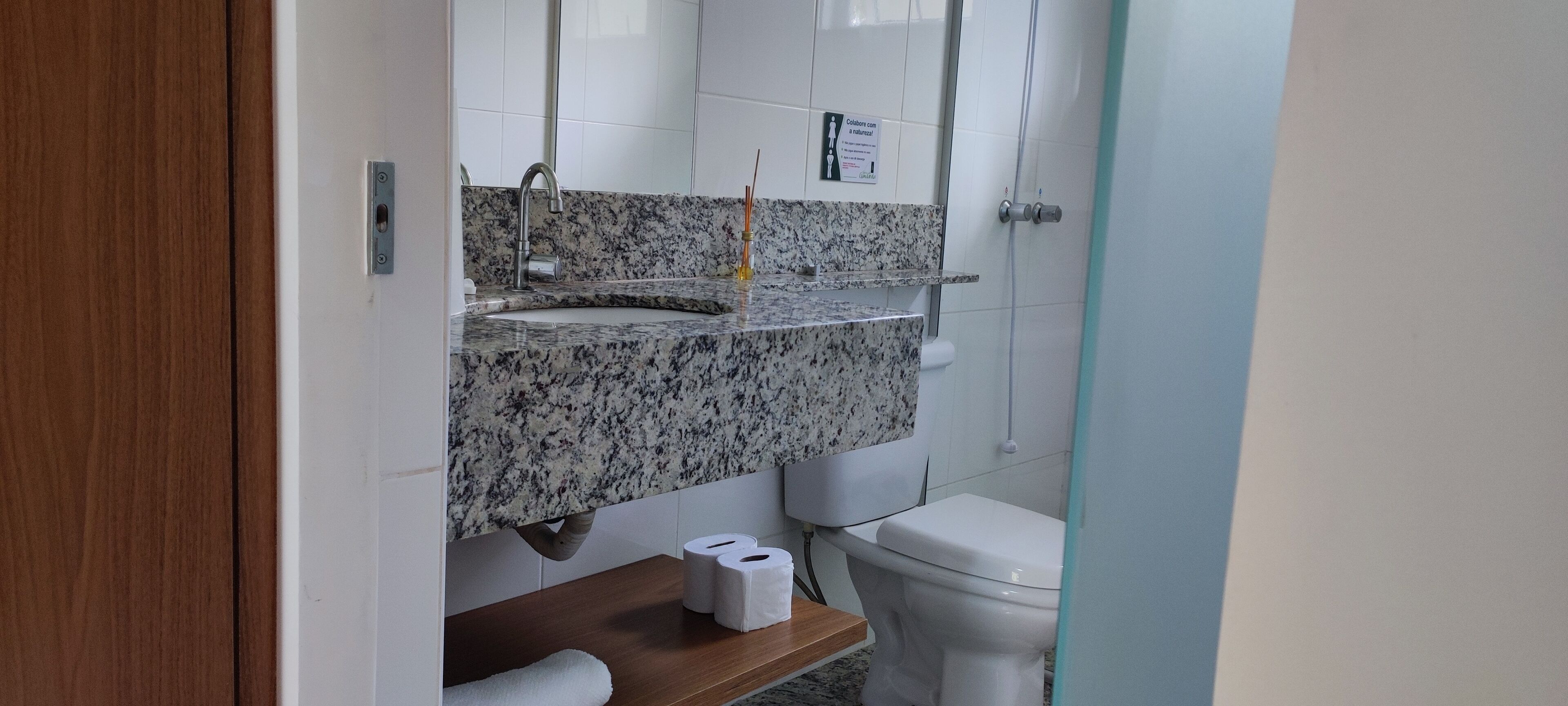 Een badkamer met een wastafel met granieten blad, een toilet en een douchehoek.