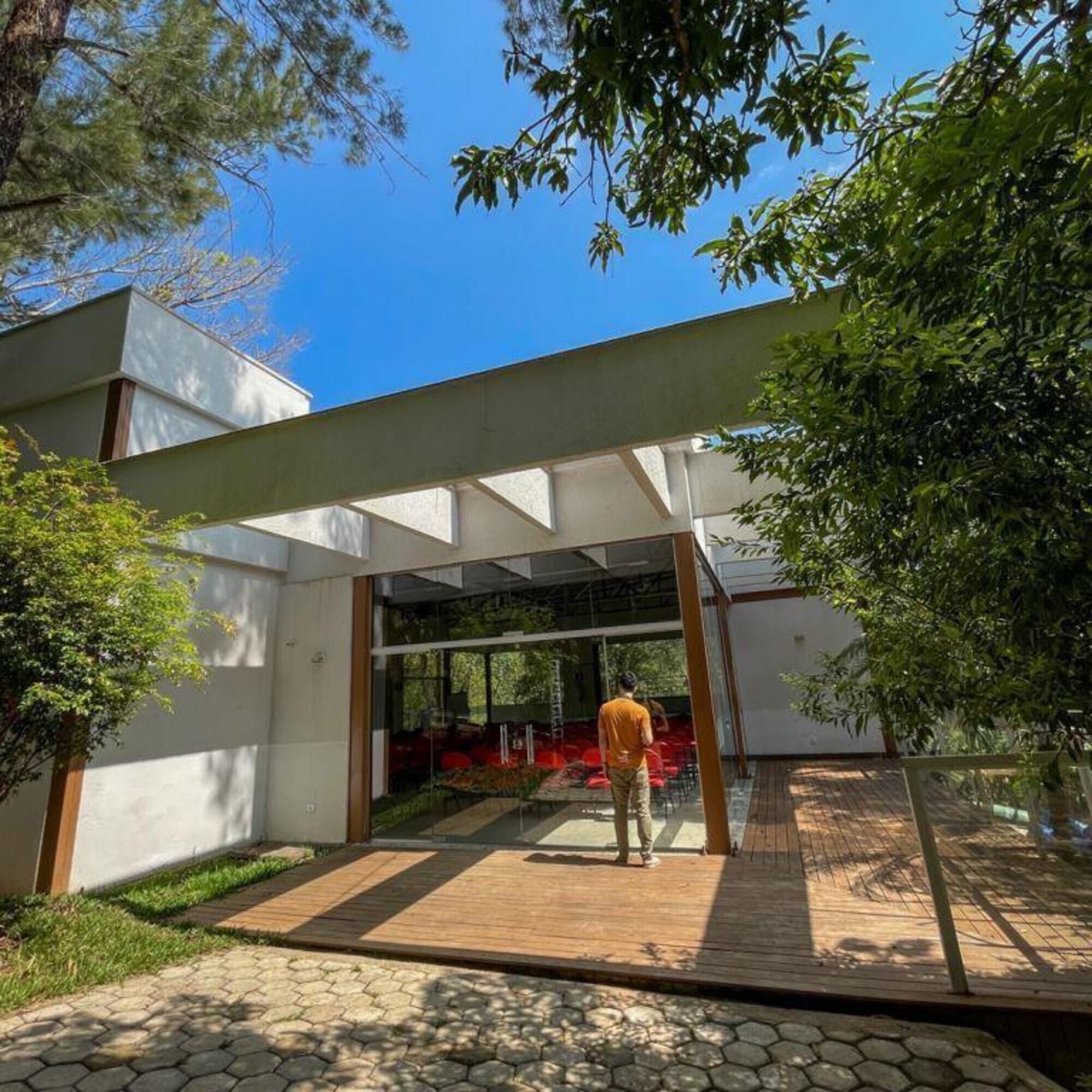 A modern building with a glass entrance, a wooden deck, and a garden area.
