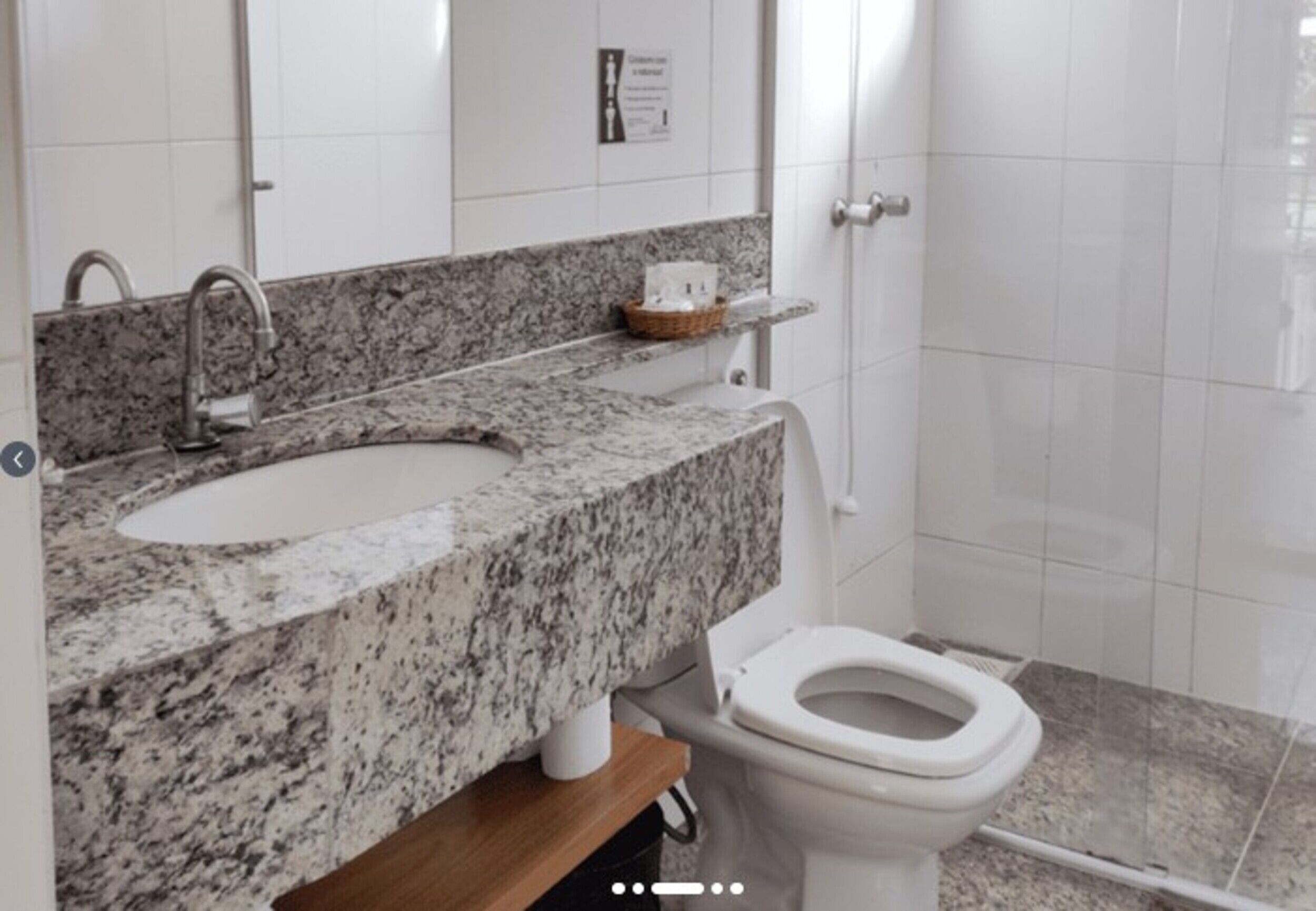 A bathroom with a granite countertop sink, a toilet, and a mirror.