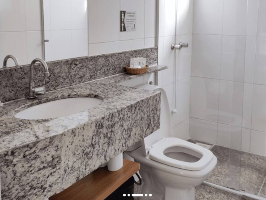 A bathroom with a granite countertop sink, a toilet, and a mirror.