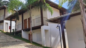 Un hilera de edificios blancos con balcones, un sendero adoquinado y palmeras.
