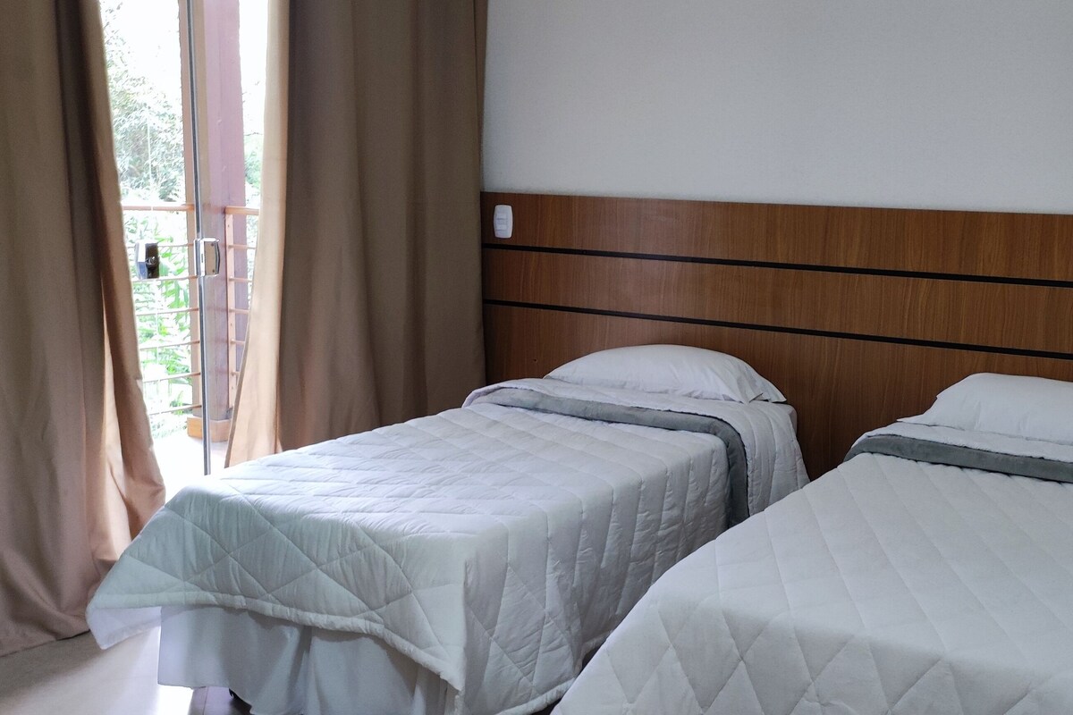 Habitación de hotel con dos camas, cabecero de madera y ventana con cortinas.