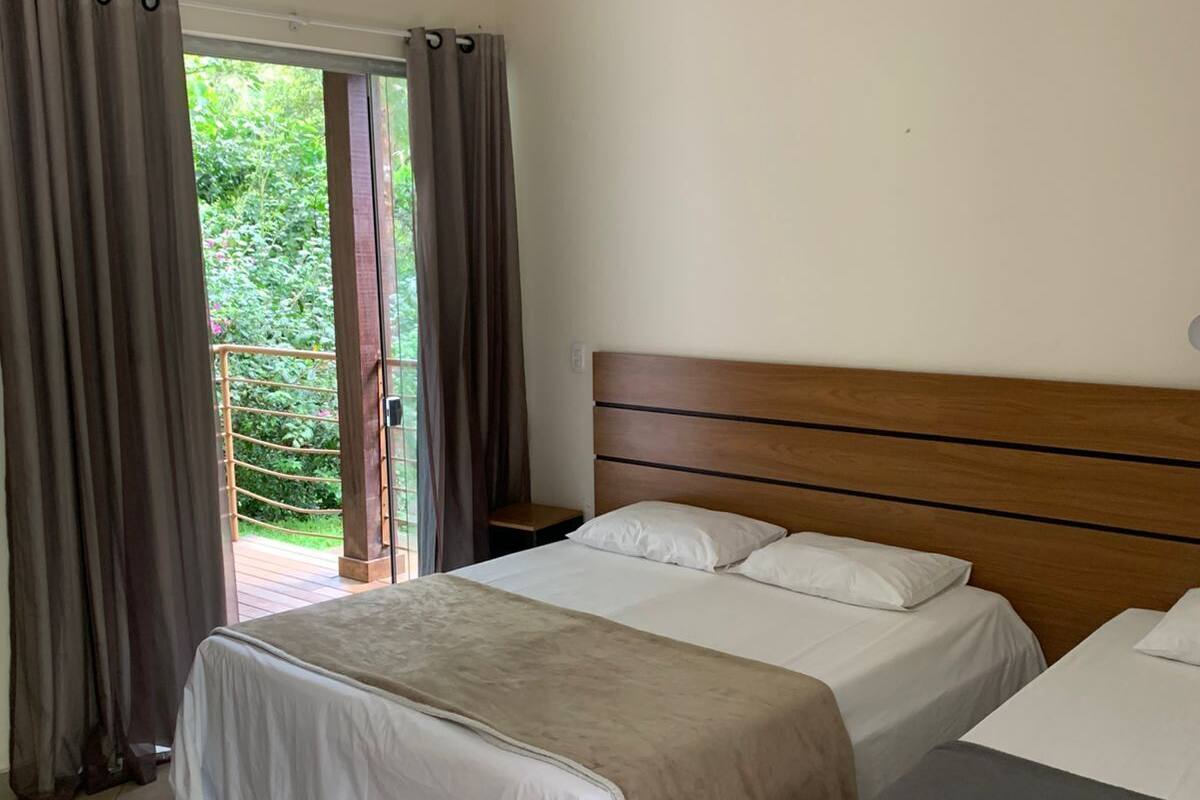 Une chambre d’hôtel avec un grand lit, un lit plus petit et un balcon avec des rideaux.