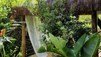 Una construcción de techo de paja rodeada de abundante vegetación y diversas plantas.