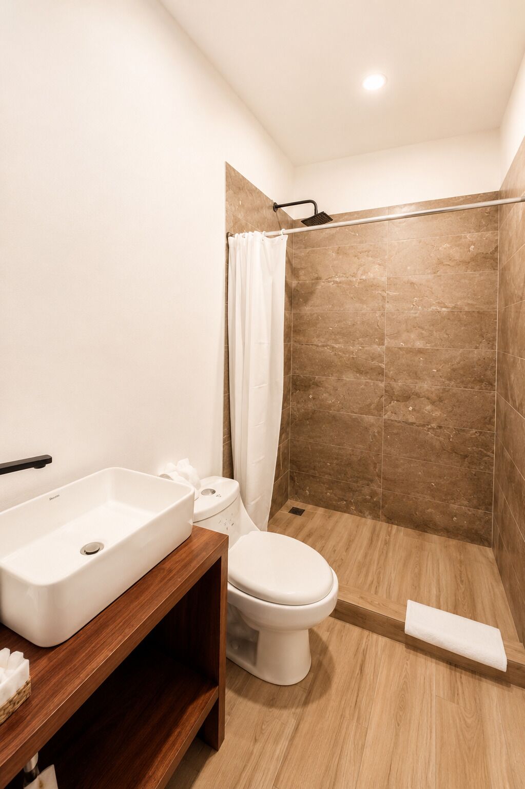 A modern bathroom with a white sink, toilet, and shower area.