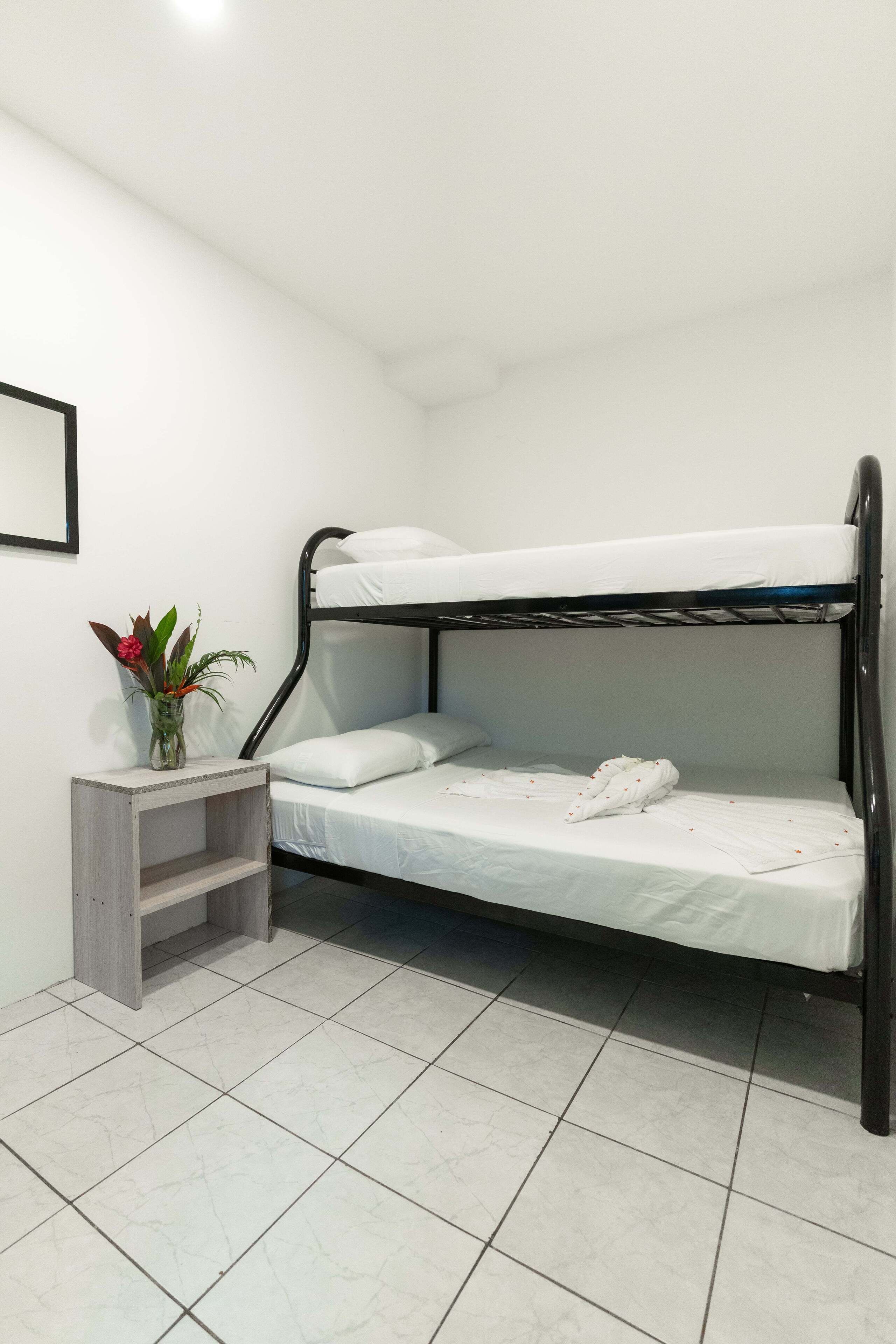 A bunk bed in a room with white walls and tiled flooring.