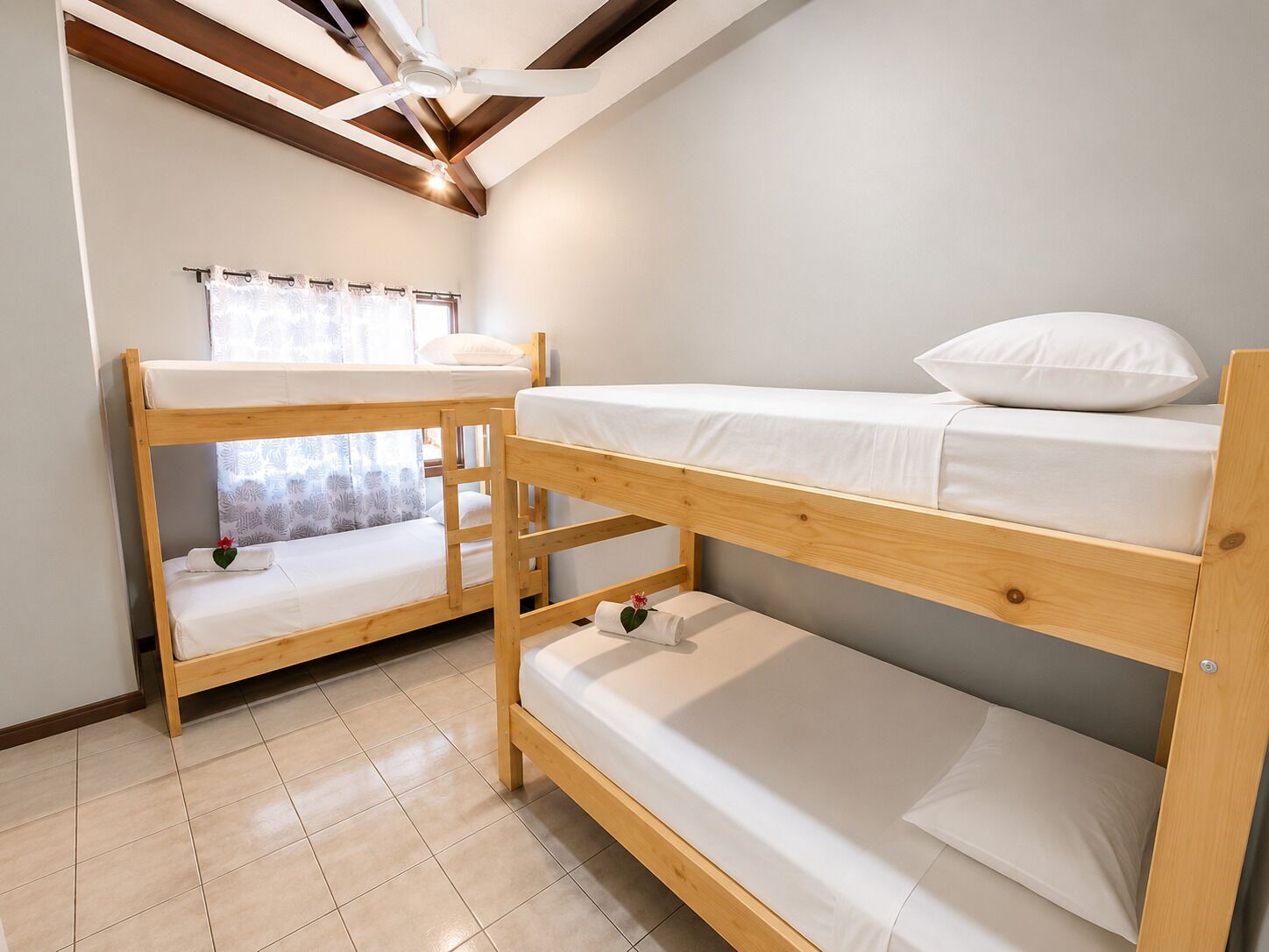 A room with two bunk beds, a ceiling fan, and a window with curtains.
