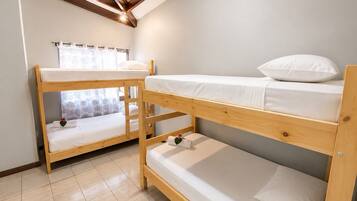 A room with two bunk beds, a ceiling fan, and a window with curtains.
