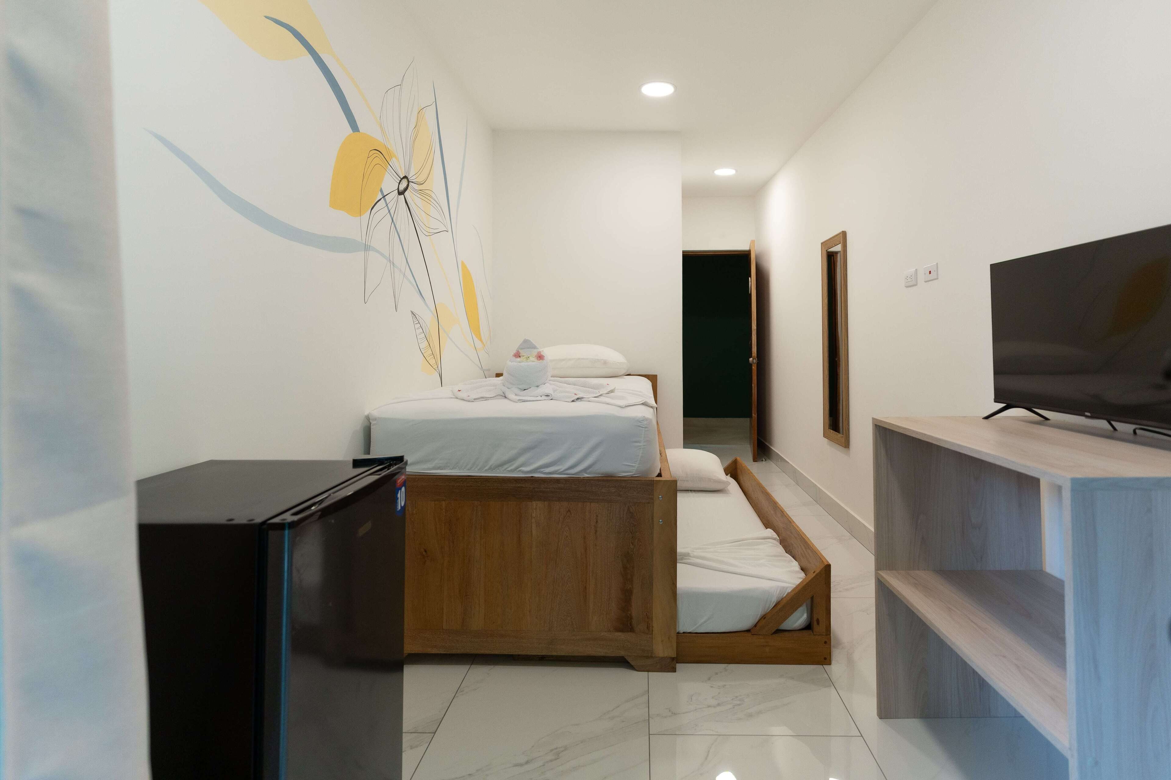 A modern hotel room with a bed, a TV, and a desk.