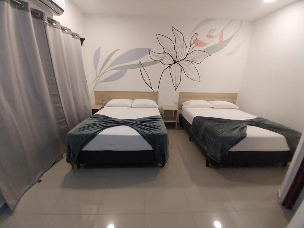 A room with two beds, a large floral wall decoration, and a curtain.