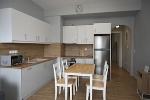 A modern kitchen with white cabinets, a wooden countertop, a stainless steel refrigerator, and a dining table with chairs.