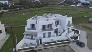 A modern white two-story house with a flat roof, solar panels, and a small balcony. - Τinos Deluxe Home (Τήνος)
