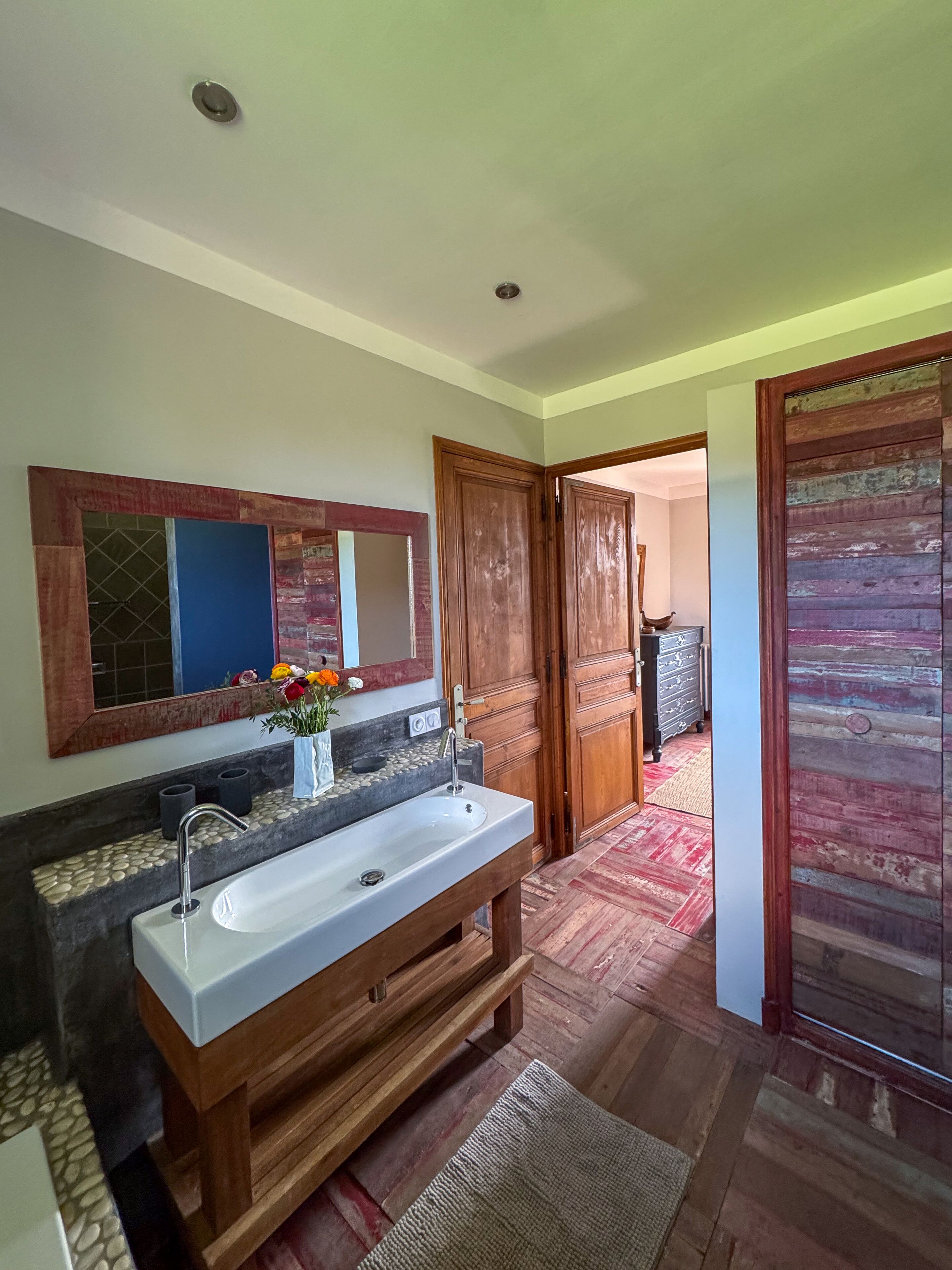 A bathroom with a double sink, a mirror, and wooden doors.