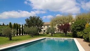 A rectangular swimming pool with a clear blue water surface, surrounded by a well-maintained lawn and various trees.