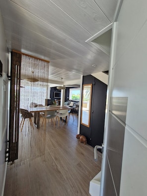 A modern interior with a dining area, kitchen, and a dog.