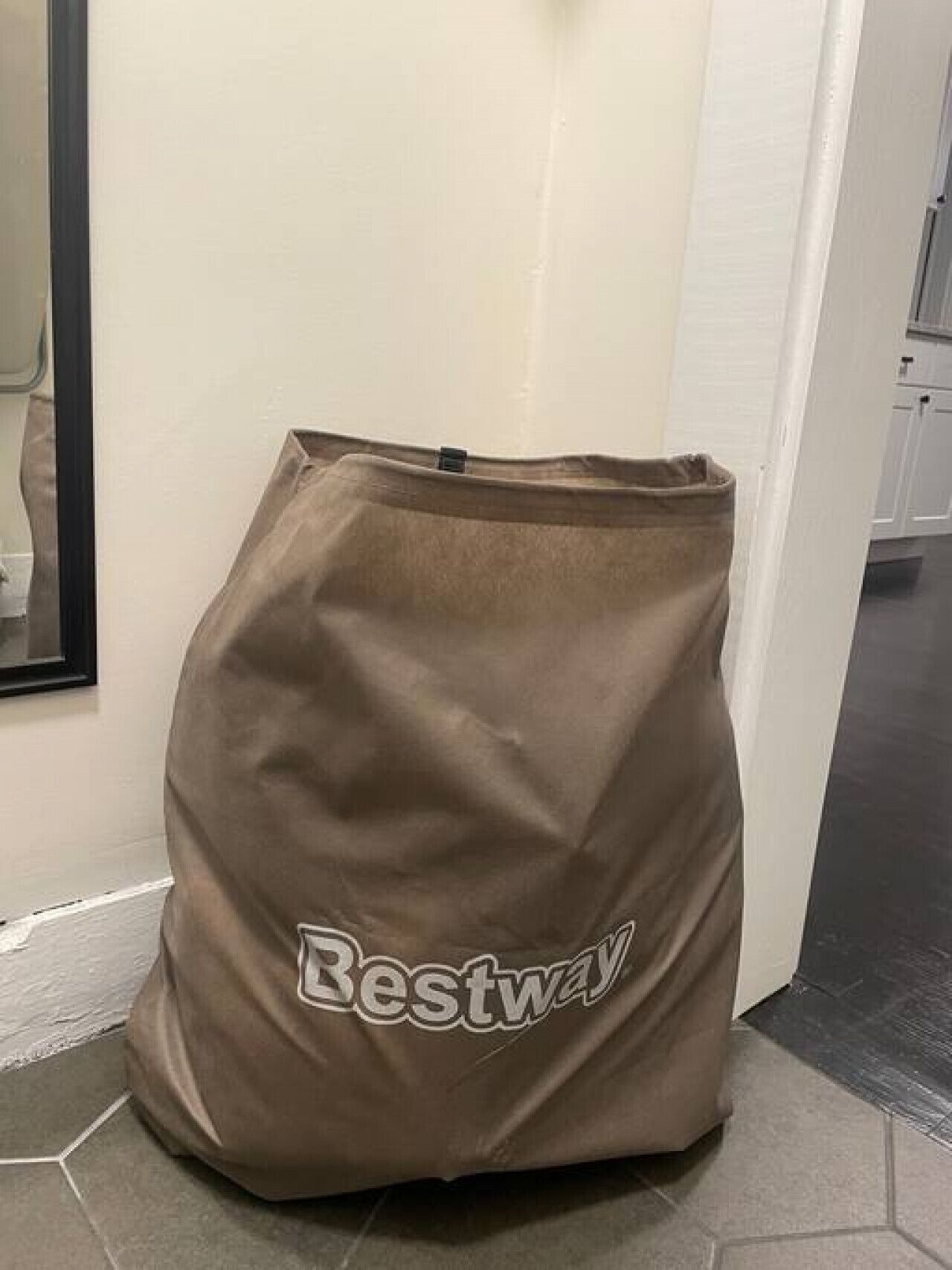 A brown bag with the word "Bestway" on it, placed on a tiled floor near a white door.